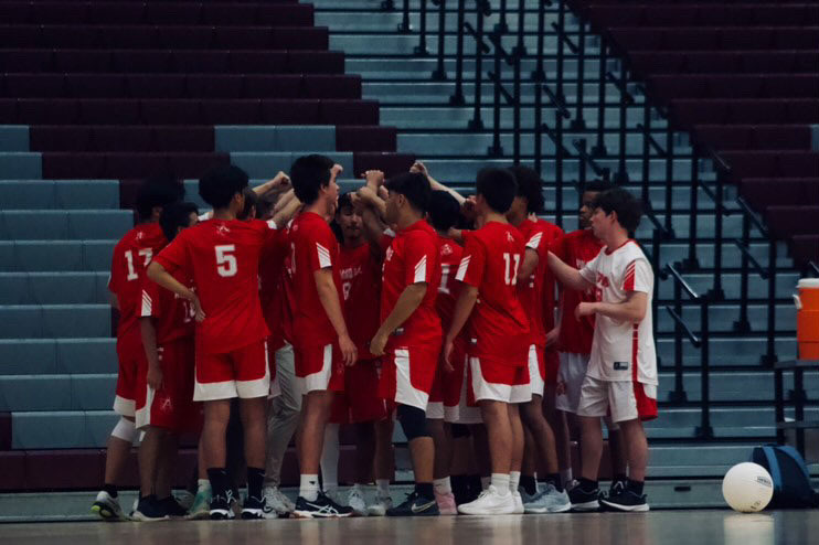 The Atoms boys volleyball team huddles up before the start of their regular season match.