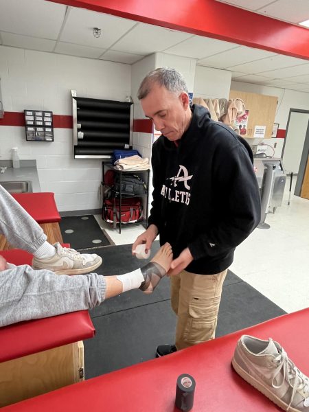 Athletic Trainer Ryan Hughes tapes up ankle in the athletic training office